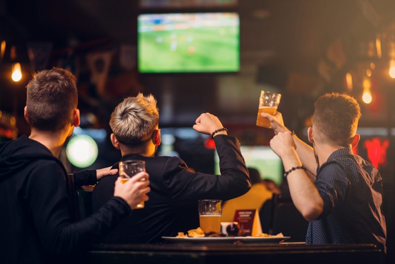 Three men watches football on TV